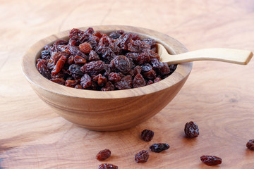 Raisin in bowl on wooden background.