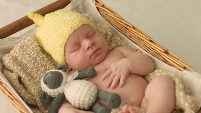 Amazing naked newborn baby in knitted hat sleeping and smiling while asleep