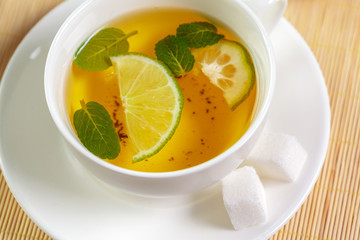 cup of black tea with mint leaves on a wooden table