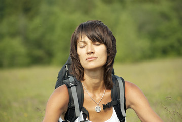 Portrait of a young woman with a backpack with closed eyes.