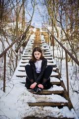 Fototapeta premium Fashionable long legs brunette model in long black cloak posed outdoor at winter day.