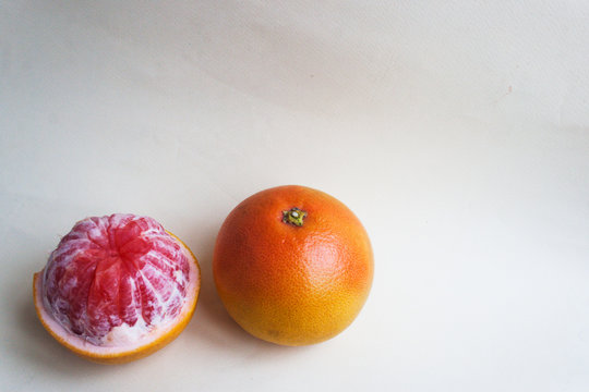 Pink grapefruit. Whole and peeled against a light background. Candid.