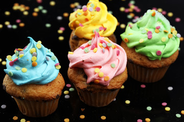 Tasty cupcakes on dark background. Birthday cupcake in rainbow colors.
