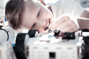 Future great technician. Selective focus on a radiant child grinning broadly while working in a workshop and designing his own self driving robot.