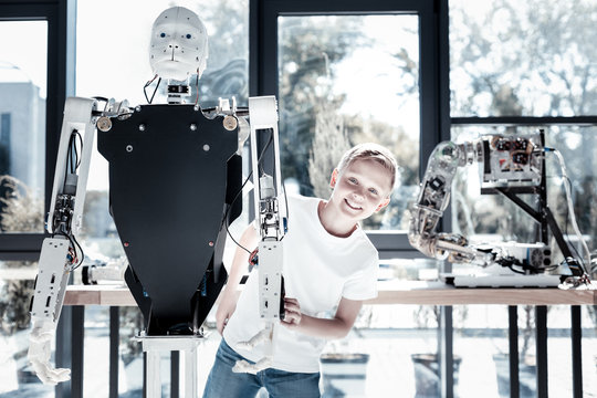Isnt this cool. Extremely happy child looking into the camera with a cheerful smile on his face while touching a human like robot and getting excited over it.
