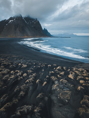 Aerial photohgraph of Black sand beach with brown overgrown sand dunes and ocean in the background in Stokksnes, Iceland 