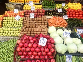 A lot of fruits and vegetables in boxes in the market with price tags.
