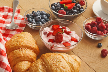 Continental breakfast with croissants and berries on natural wood