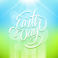 Earth Day holiday card with hand drawn lettering text design, sun and blurred background. Vector illustration.