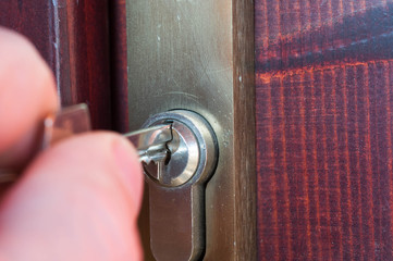 Caucasian male hand opening a wooden door with the key close up shot.