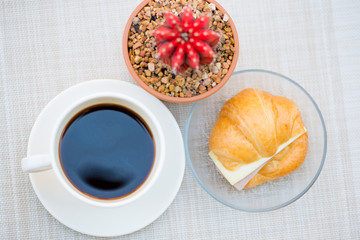 A cup of Black coffee with Ham and cheese croissant