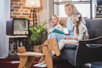 wooden rocking horse and family reading book behind, 1950s style