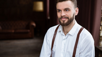 Fashion stylish confident portrair of handsome bearded guy on the big window looking away