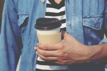 Young man guy hand holding paper cup of take away drinking coffee. lifestyle young Office. filter vintage.