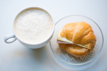 A cup of Black coffee with Ham and cheese croissant