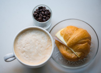 A cup of coffee with Ham and cheese croissant