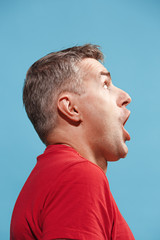 Obraz premium The young attractive man looking suprised isolated on blue