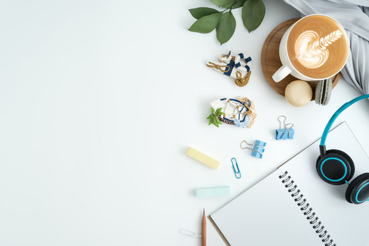 Styled stock photography white office desk table with blank notebook, keyboard, macaroon, supplies and coffee cup. Top view with copy space. Flat lay.