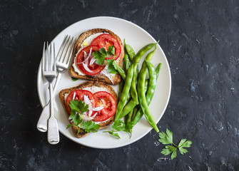 Tomato and cheese sandwiches and green beans - healthy vegetarian  snack on a dark table, top view