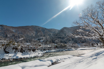Tourists crossing the Deai-bashi suspension bridge to the village  in winter in Shirakawa-go,Ono ,Gifu,Japan.