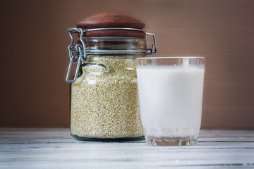 Sesame seed milk in a glass. White sesame seeds on a table. Raw food diet.