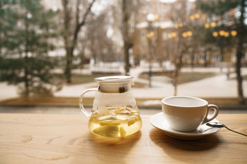 tea from a sea-buckthorn in a transparent teapot on a wooden table on a window facing the street and spring.