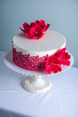 Obraz na płótnie Canvas White wedding cake decorated with flowers sugar poppies and red pattern ornament. Concept of elegant holiday desserts