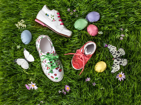 Kinderschuhe, Ostereier und Schmetterlinge auf Rasen