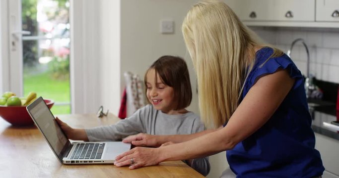 Businesswoman working on her laptop at home and gets interrupted by her daughter