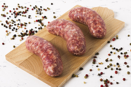 Raw sausages on cutting board and white background.