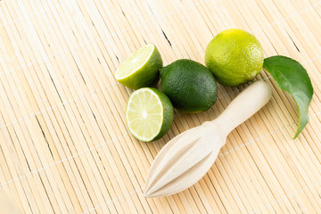 Healthy food and vitamins: a wooden juicer and fresh lime with leaves and freshly squeezed delicious juice on a bamboo napkin