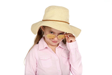 Fototapeta premium Kleines Mädchen mit Strohhut schaut über den Rand ihrer Sonnebrille und lächelt