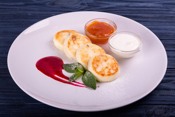 Cottage cheese pancakes Russian syrniki with cranberry jam and yogurt, selective focus