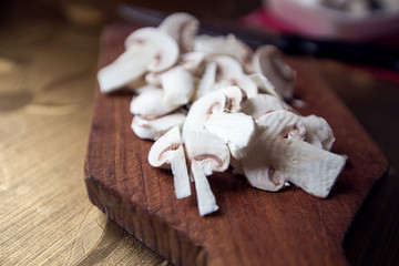 Slice of white button mushrooms on wooden board