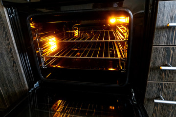 Empty open electric oven with hot air ventilation. New oven. Door is open and light is on