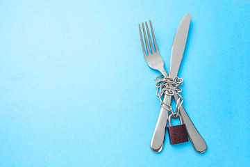 Hunger strike as a diet for weight loss. Fork and knife are wrapped in chain and locked against...