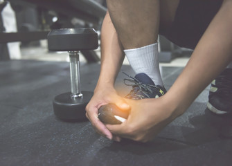 Athlete runner holding his foot in pain. He suffering from foot injury while exercising and running. Sport exercise injuries concept.