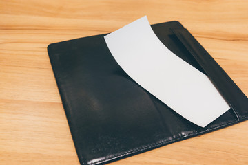 Blank empty white paper in restaurant payment billing receipt folder on wood table