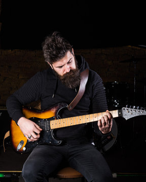 Man with busy face in black clothes holds guitar, play