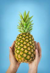 Female hand with pineapple at pink background