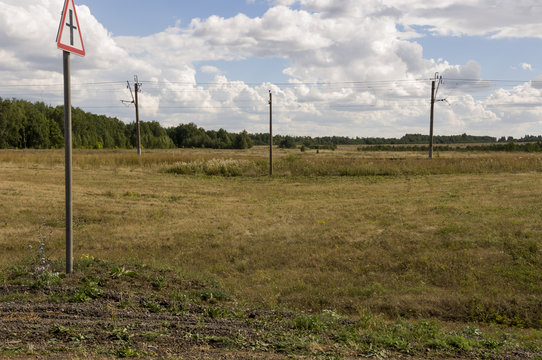 Huge white clouds in the cold autumn sky over green fields, trees, forests, streams. sunne day. Electric poles