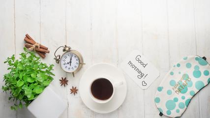 Alarm clock, coffee and flowers. Morning mood, on a white background, top view, with a blank space for an inscription or advertisement.
