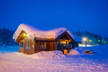 Amazing night view of traditional wooden houses with snow in the roof in stunning nature background in Valdres region in Norway