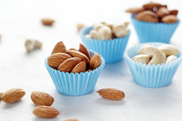 Almonds in the blue paper baking molds on white table.
