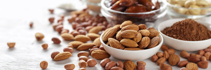 Almond, peanut, cocoa powder and cashew on white wooden table.