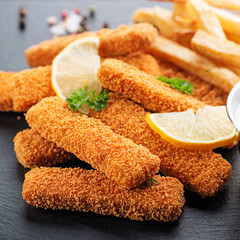 Fish fingers and fries with sauce on dark background. 