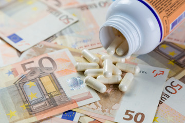 Overpriced drugs concept - pills from container on monet bills