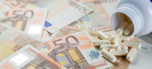 Overpriced drugs concept - pills from container on monet bills