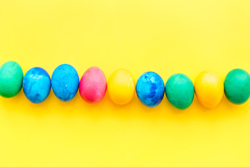 Colorful easter eggs with blossom branch on yellow background top view mockup