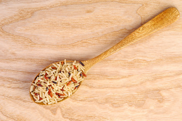 Wooden spoon with dried rice grains of different breeds